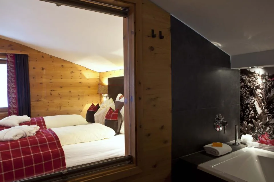 Blick durch ein Innenfenster vom Bad in das Schlafzimmer aus Zirbenholz