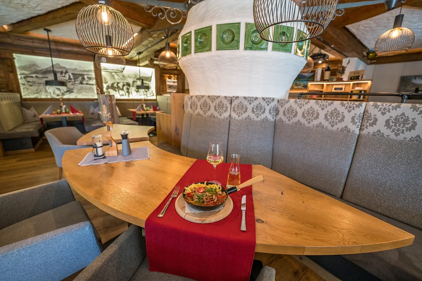 Gaststube mit Holzvertäfelung, grünem Kachelofen und gedecktem Tisch