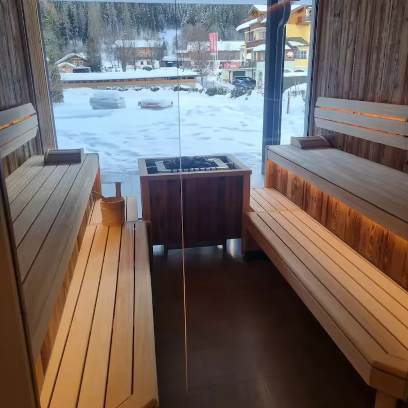 Sauna mit Panoramafenster und Blick auf verschneite Häuser und Wald